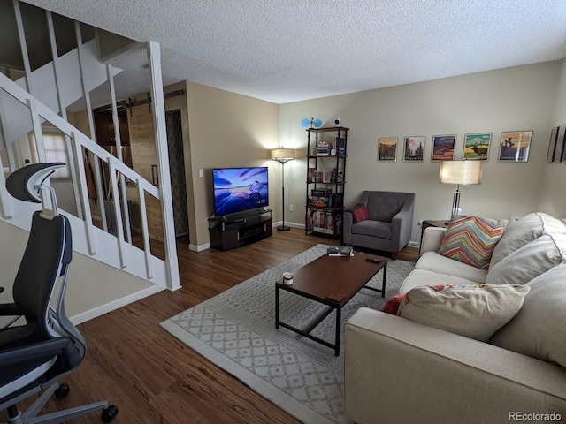 living area featuring stairs, a textured ceiling, baseboards, and wood finished floors