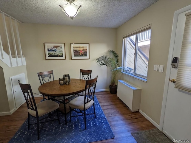dining room with wood finished floors, baseboards, a textured ceiling, and radiator heating unit