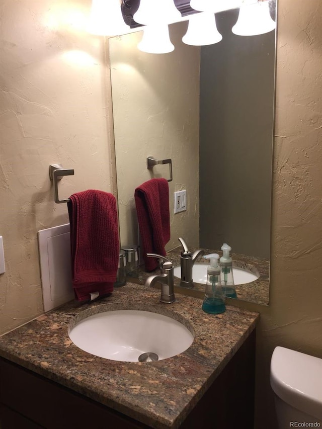 half bathroom featuring vanity and toilet