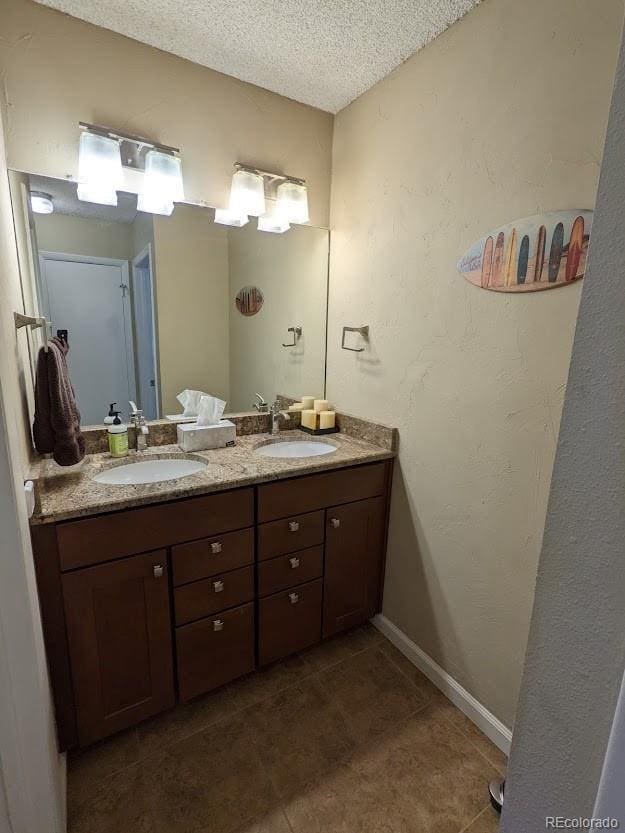 full bathroom with a sink, a textured ceiling, tile patterned floors, and double vanity