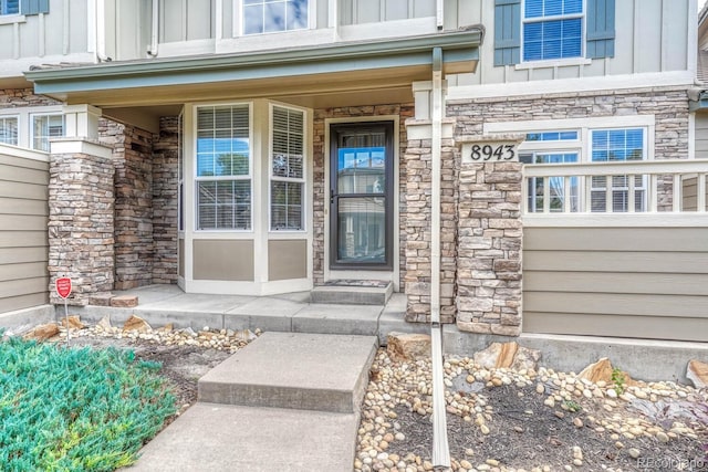 8943 Tappy Toorie Cir, Highlands Ranch, CO 80129 - property entrance featuring board and batten siding, stone siding, covered porch, and a garage
