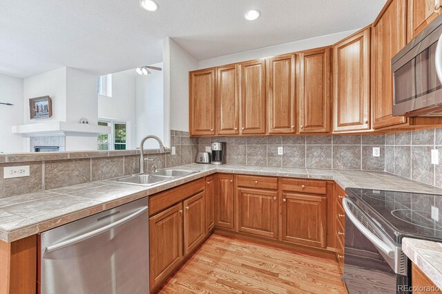 8943 Tappy Toorie Cir, Highlands Ranch, CO 80129 - kitchen featuring appliances with stainless steel finishes, a sink, a ceiling fan, light wood-style flooring, and brown cabinets