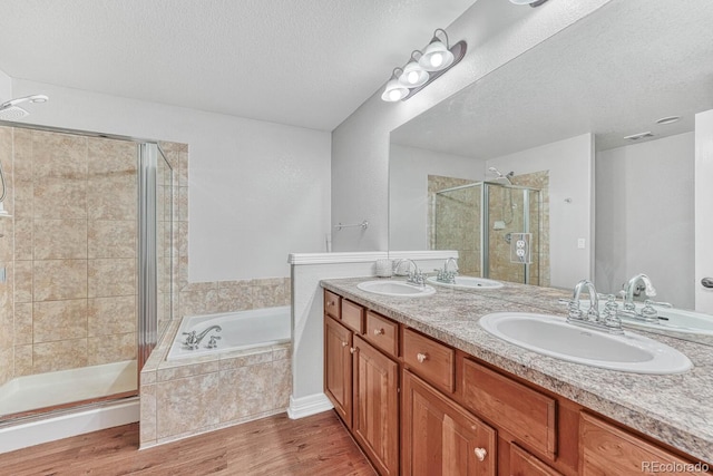 8943 Tappy Toorie Cir, Highlands Ranch, CO 80129 - bathroom featuring a stall shower, a garden tub, double vanity, wood finished floors, and a textured ceiling