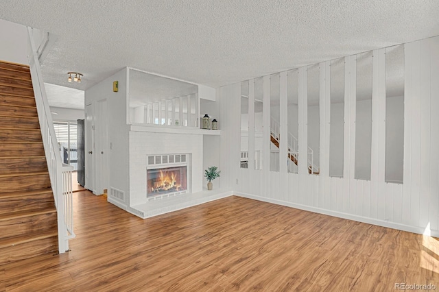 unfurnished living room featuring visible vents, a textured ceiling, and stairs