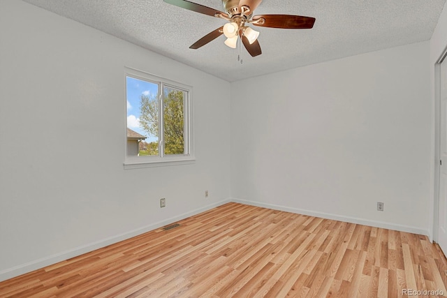 spare room with visible vents, a textured ceiling, light wood-style floors, and baseboards
