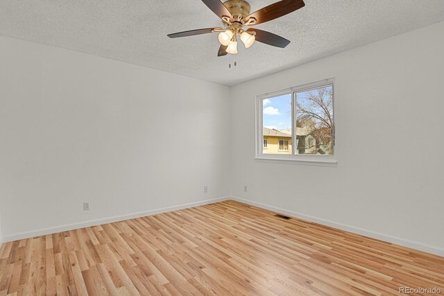 spare room with ceiling fan, a textured ceiling, baseboards, light wood-type flooring, and visible vents
