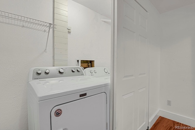 washroom featuring laundry area, wood finished floors, and washer and clothes dryer