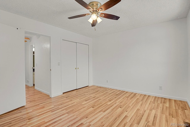 unfurnished bedroom featuring a textured ceiling, baseboards, light wood finished floors, and a closet