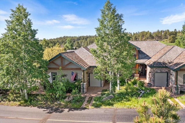378 Fox Acres Dr W, Red Feather Lakes, CO 80545 - view of front of home with an attached garage, stone siding, a tile roof, and a forest view