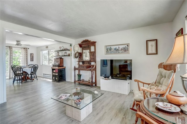 living room featuring hardwood / wood-style floors, a baseboard heating unit, and a textured ceiling