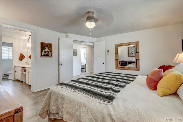 bedroom with ceiling fan, connected bathroom, and light hardwood / wood-style floors