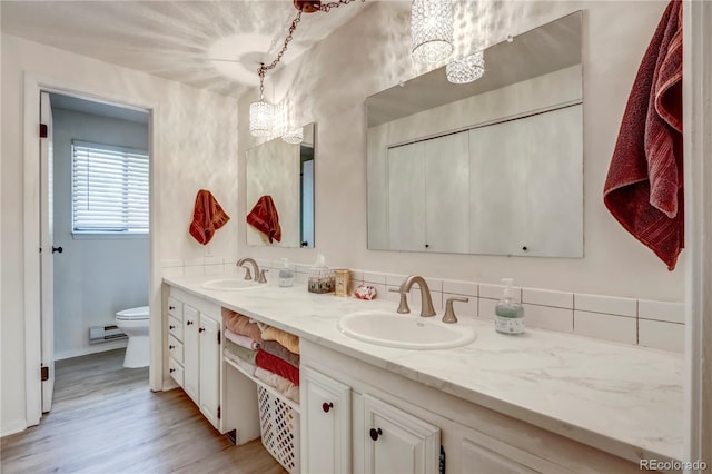 bathroom featuring double sink, hardwood / wood-style floors, a chandelier, large vanity, and toilet