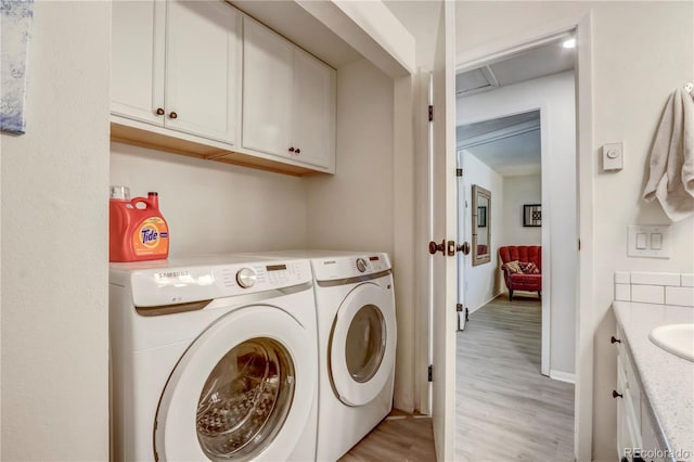 clothes washing area featuring separate washer and dryer and light hardwood / wood-style floors