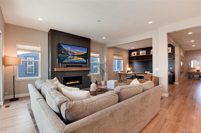 living room with a fireplace and light wood-type flooring