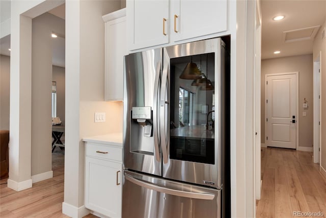 kitchen with white cabinetry, light hardwood / wood-style floors, and stainless steel fridge