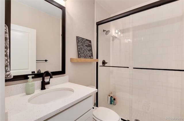 bathroom featuring toilet, a shower with door, and vanity