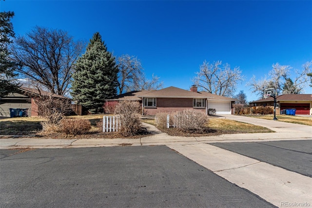 view of front of home with an attached garage, a chimney, concrete driveway, a fenced front yard, and brick siding