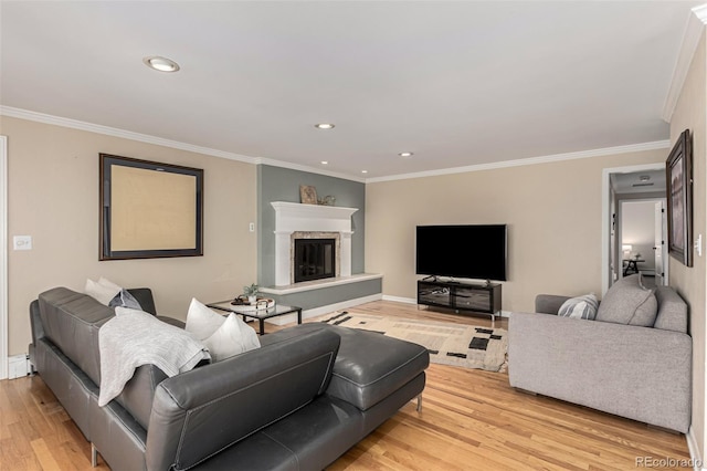 living room with recessed lighting, a glass covered fireplace, crown molding, light wood-type flooring, and a baseboard heating unit