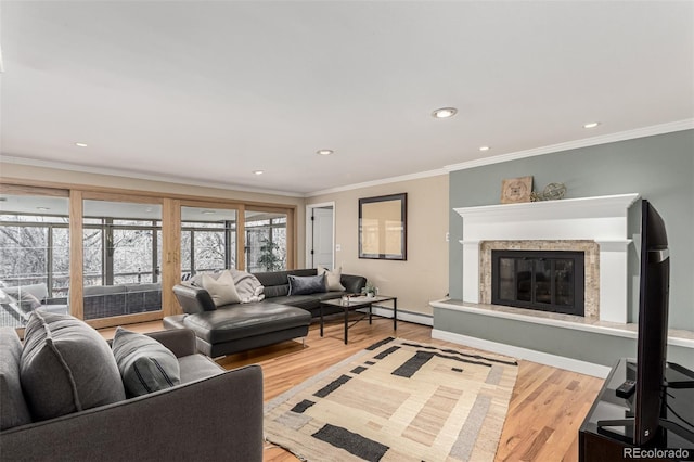 living area with wood finished floors, a healthy amount of sunlight, a glass covered fireplace, and ornamental molding