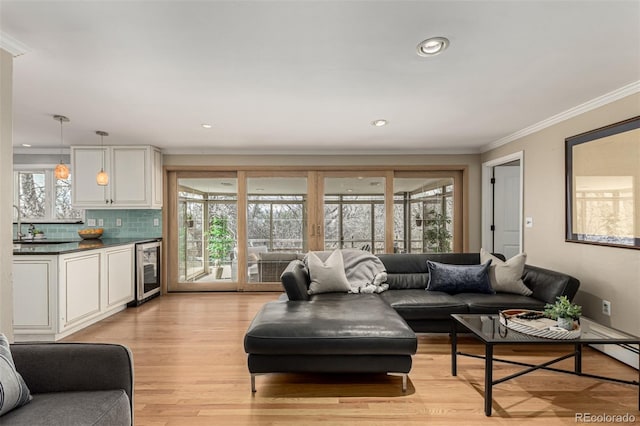 living room featuring beverage cooler, recessed lighting, light wood-style flooring, and crown molding