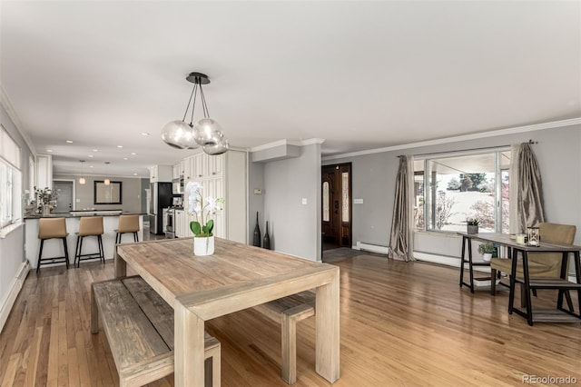 dining space with light wood finished floors, recessed lighting, a baseboard radiator, and ornamental molding