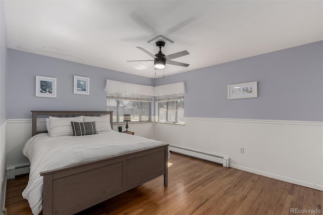 bedroom with baseboards, wood finished floors, a ceiling fan, and a baseboard radiator