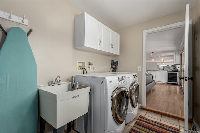 laundry room featuring a sink, beverage cooler, light tile patterned floors, cabinet space, and separate washer and dryer