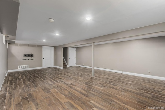 finished below grade area with visible vents, stairway, baseboards, and wood finished floors