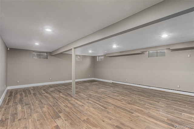 finished below grade area featuring recessed lighting, wood finished floors, baseboards, and a baseboard radiator