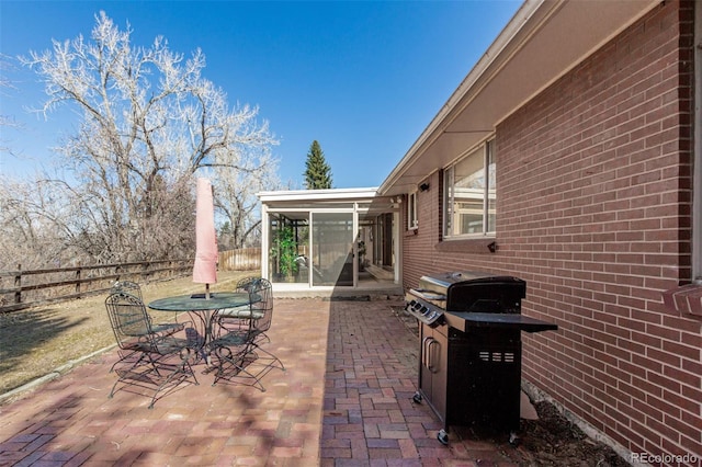 view of patio with outdoor dining area, fence, and a sunroom