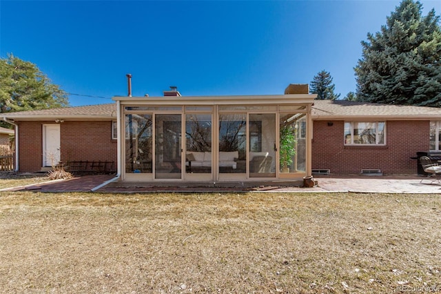 back of house featuring a yard, a patio area, brick siding, and a sunroom