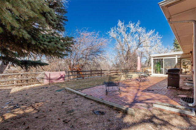 view of yard featuring a patio area, a fenced backyard, and a sunroom