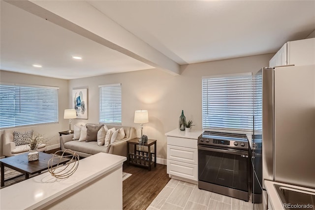 kitchen with stainless steel fridge, electric range, white cabinets, and light wood-type flooring