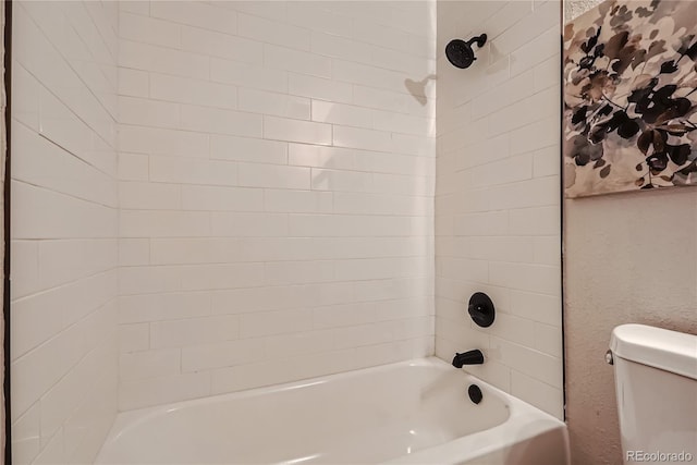 bathroom featuring toilet and tiled shower / bath