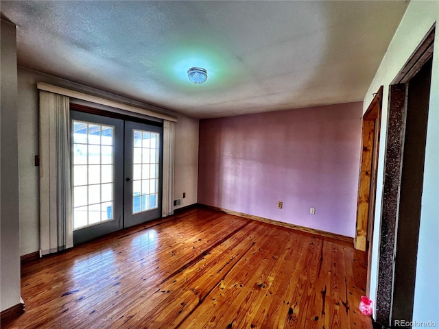 empty room featuring french doors, a textured ceiling, and wood-type flooring