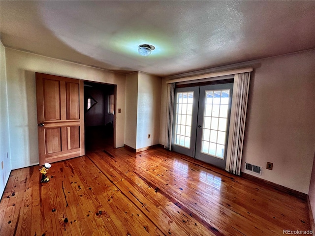 spare room featuring french doors, a textured ceiling, and hardwood / wood-style floors