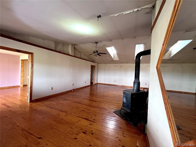 basement featuring a wood stove, wood-type flooring, and ceiling fan