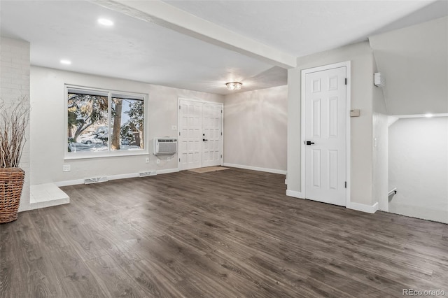 unfurnished living room featuring beam ceiling, dark hardwood / wood-style floors, and an AC wall unit