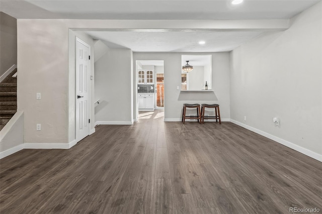 unfurnished living room featuring dark hardwood / wood-style flooring and beamed ceiling