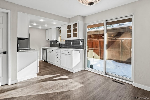 kitchen with decorative backsplash, white cabinetry, hardwood / wood-style flooring, and dishwasher