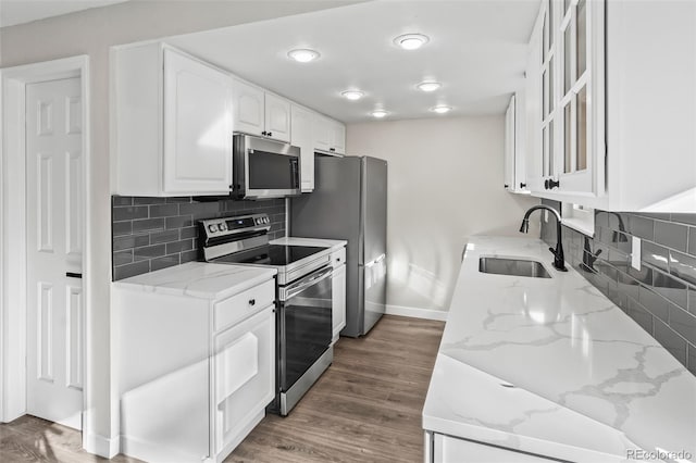 kitchen featuring white cabinets, appliances with stainless steel finishes, dark wood-type flooring, sink, and light stone counters