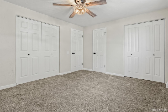 unfurnished bedroom featuring ceiling fan, carpet flooring, and two closets