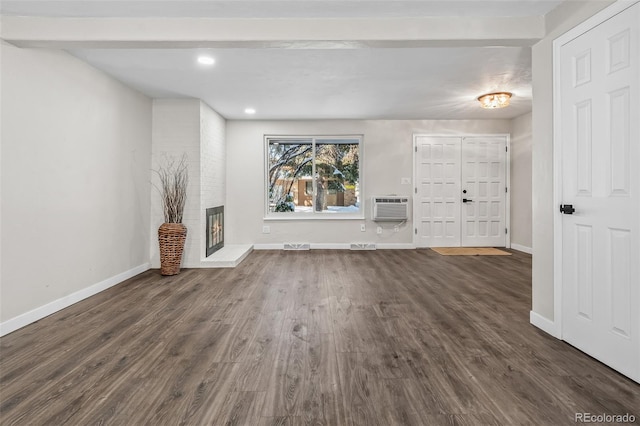 unfurnished living room featuring a brick fireplace, dark hardwood / wood-style floors, an AC wall unit, and beamed ceiling