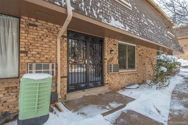 snow covered property entrance featuring brick siding