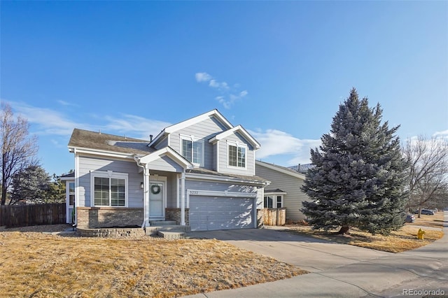 traditional-style home featuring a garage, stone siding, fence, and concrete driveway