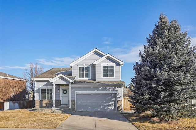 traditional-style house with an attached garage, a shingled roof, fence, concrete driveway, and stone siding