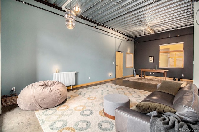 living room featuring a towering ceiling, concrete floors, and radiator