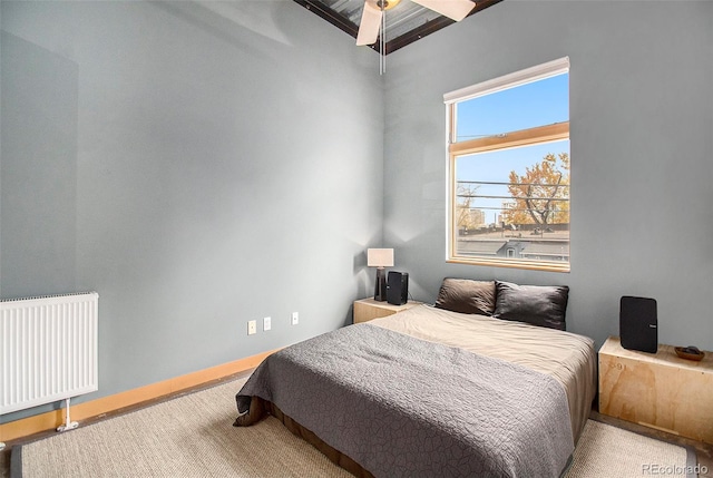 carpeted bedroom featuring beam ceiling, ceiling fan, and radiator heating unit