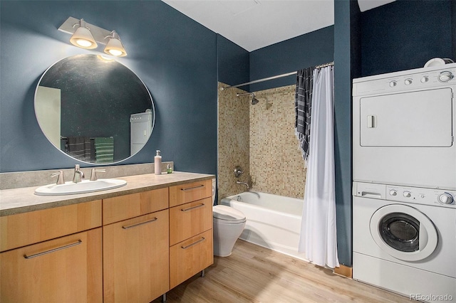 full bathroom featuring hardwood / wood-style floors, shower / bath combo with shower curtain, vanity, toilet, and stacked washer and dryer