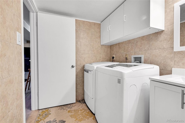 washroom featuring separate washer and dryer, light tile patterned floors, cabinets, and tile walls